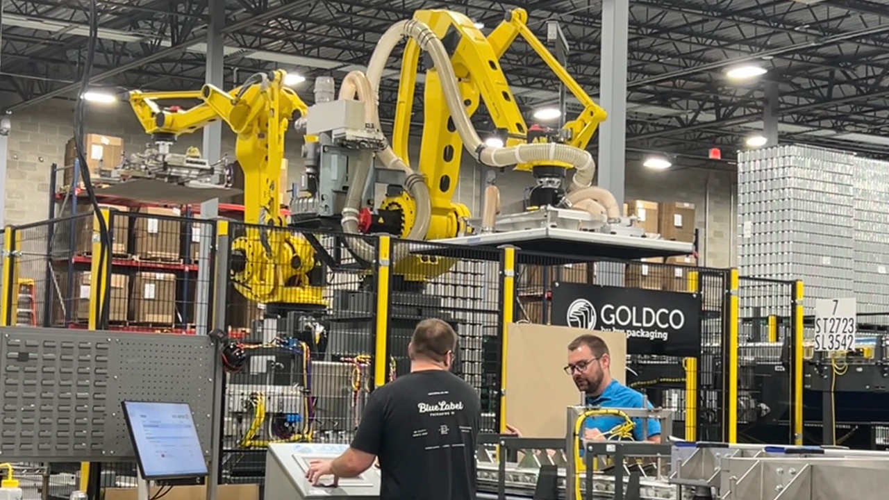Robotic arms load and unload cans onto and off the Velox machine