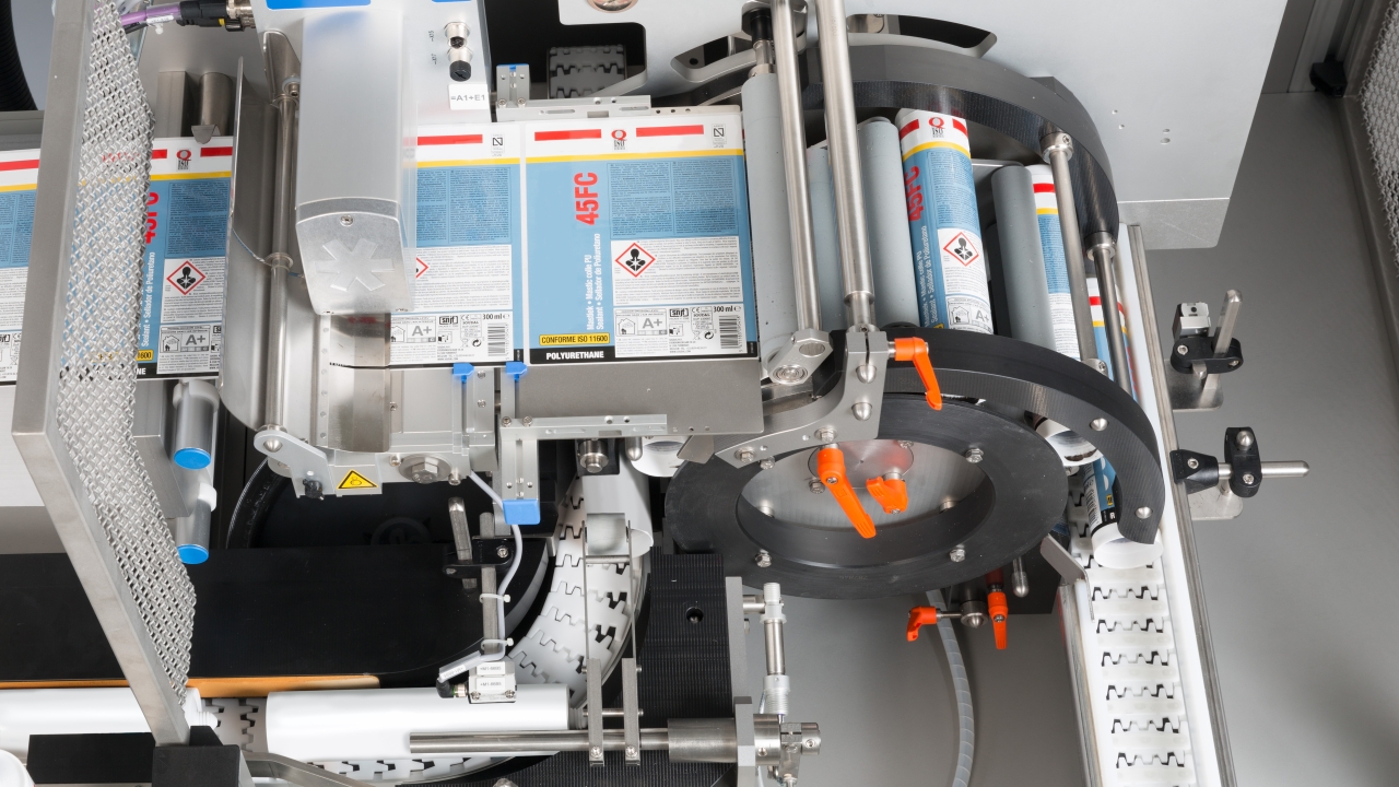 The cartridges remain horizontal as the wraparound labels are applied by the Herma 242M