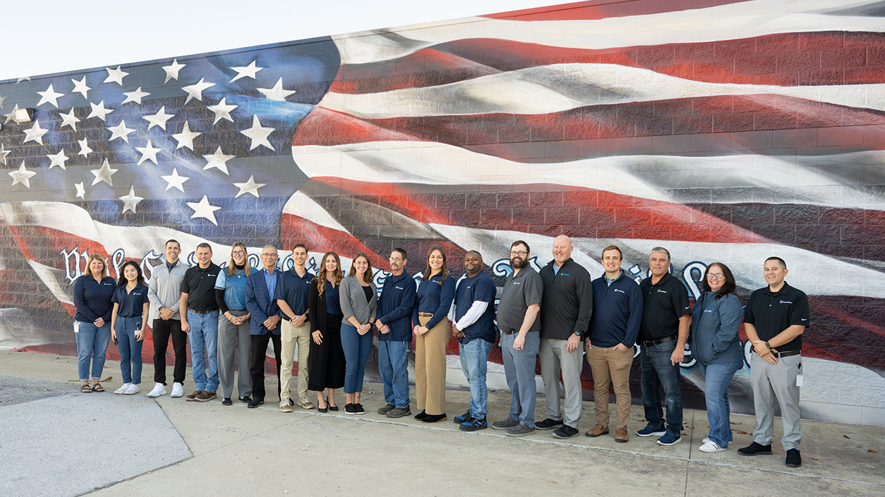 The SmartSolve team in front of a wall painted with a big American flag