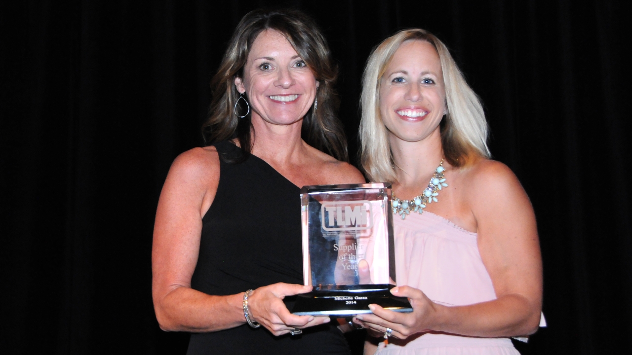 Michelle Garza wins TLMI 2014 Supplier of the Year award, with Tasha Ventimiglia of Labelexpo