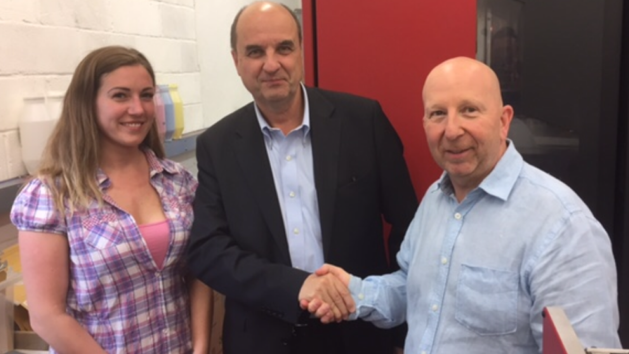 Jessica Cook (left) and Les Burden (right) of Label Solution were joined by Benoit Chatelard (center), president, Flint Group Digital Solutions, visited Label Solutions to sign the deal, 