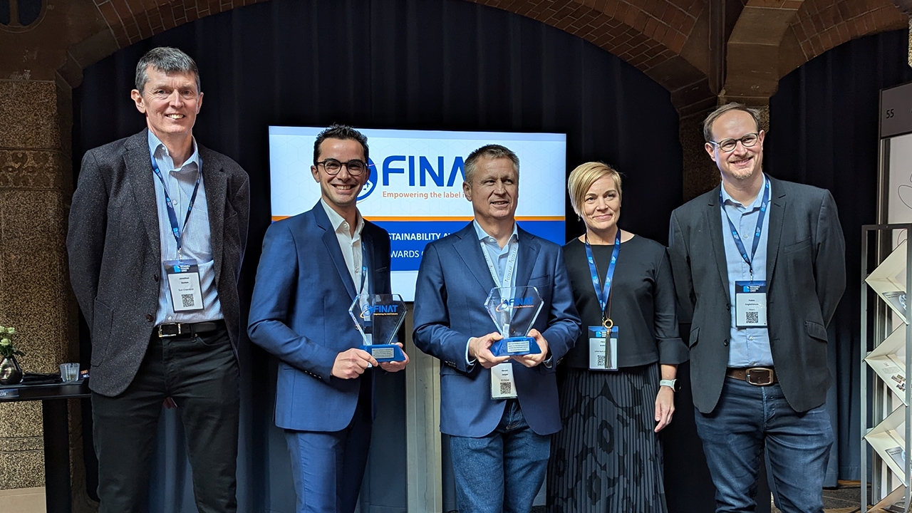 A group of people standing in front of a Finat sign, with Harald Jasper of Actega holding the award