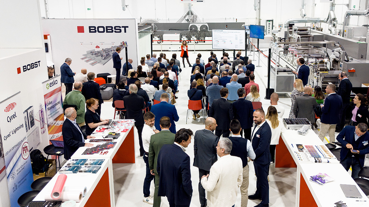 A crowd of people mill about and watch a speaker at the Bobst Competence Center in Firenze