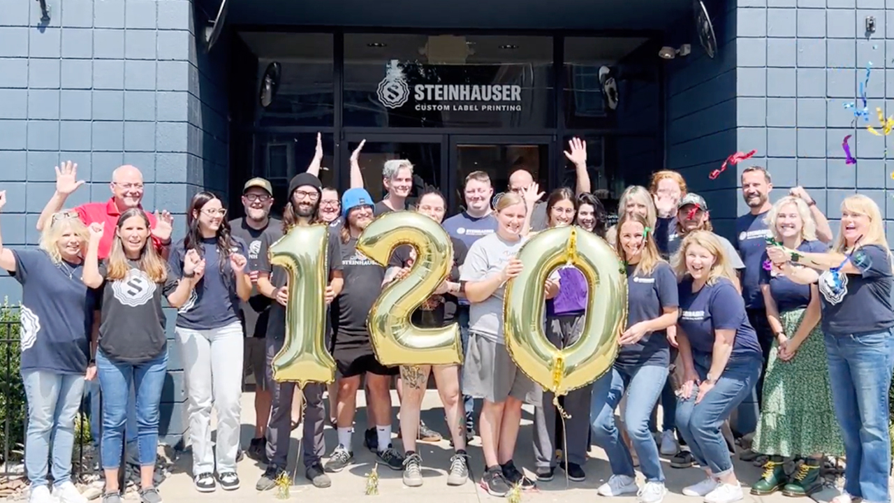 the Steinhauser team holding balloons that say 120 in front of the building