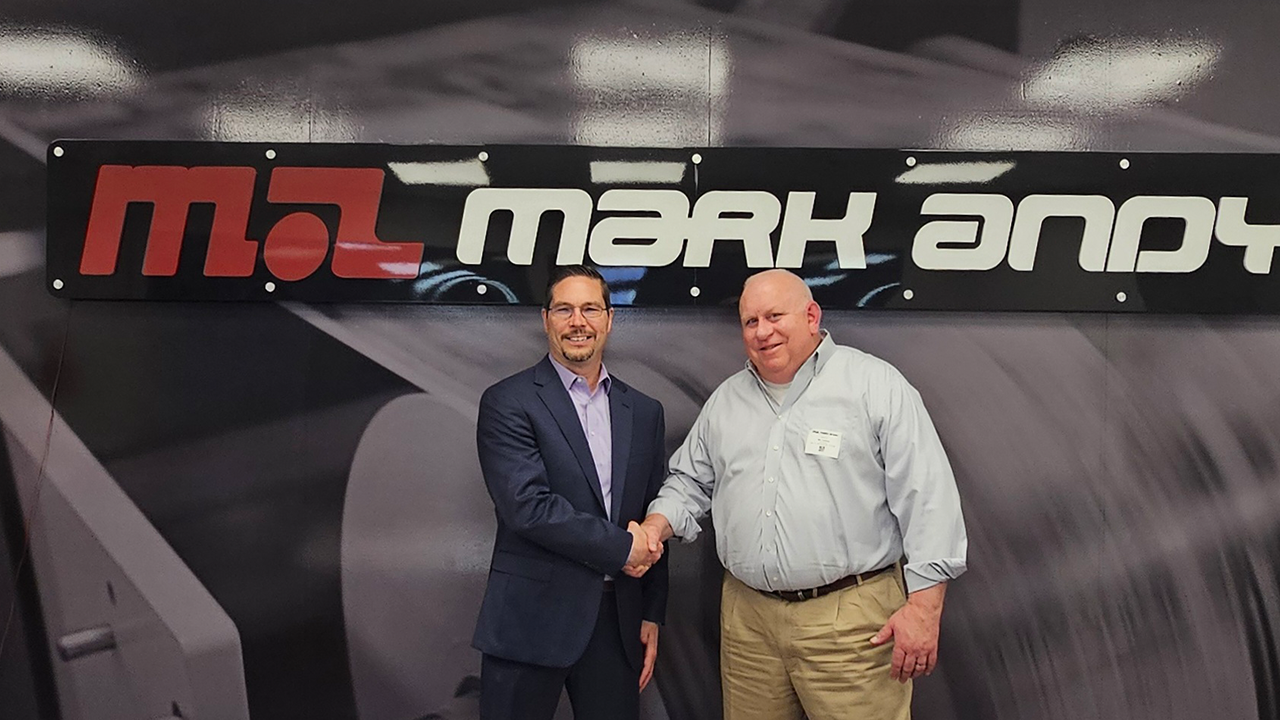 John Baer and Vic Losure shake hands in front of Mark Andy sign