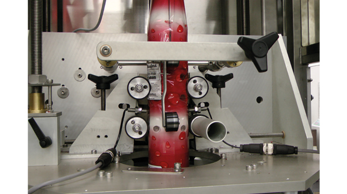 Figure 7.16 Close up showing how shrink sleeve film is fed over a mandrel and into a rotary style cutter. Source- Accraply