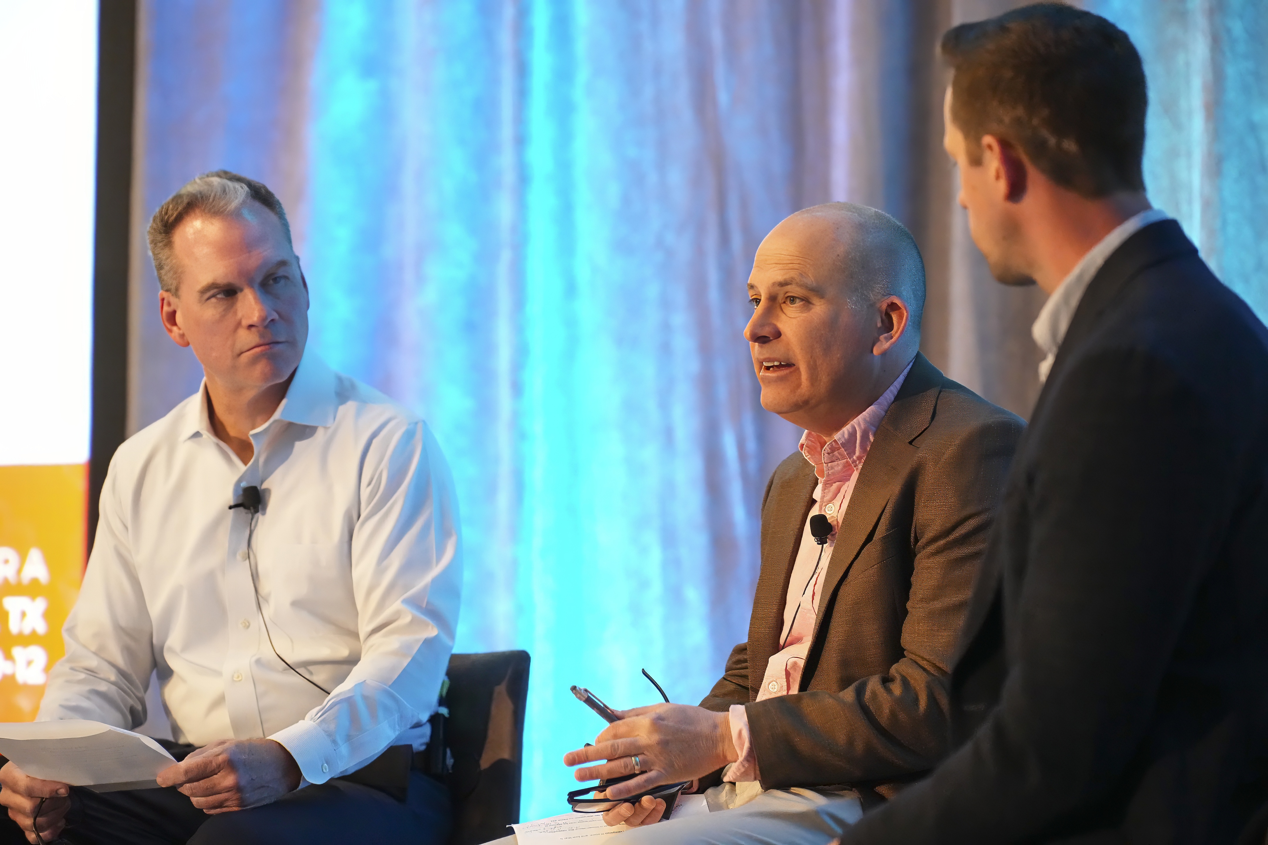 Patrick Potter, Bryan Vickers and Tyler Matusevich sit on stools on a stage