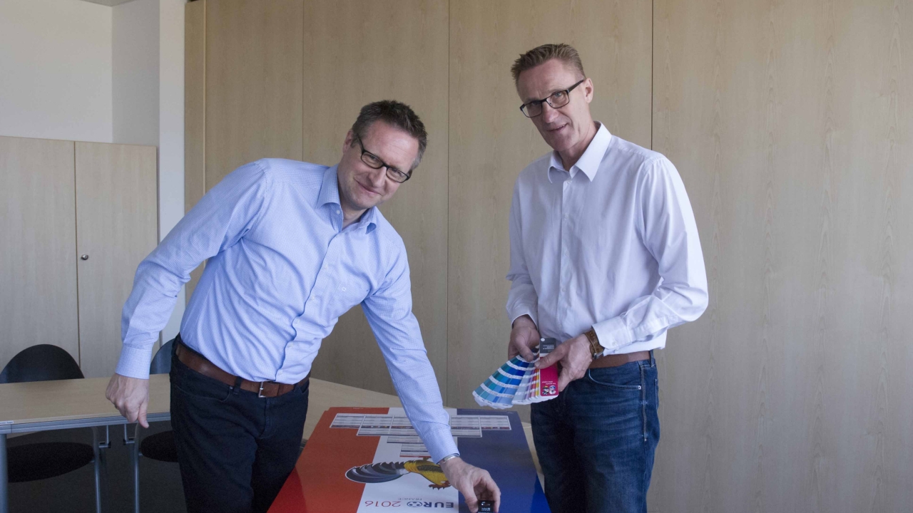 Carsten Zölzer (left) and Roland Schröder (right), both product manager for UV inks at hubergroup, examining a UEFA Euro 2016 match planner printed with the new UV inks Carsten Zölzer (left) and Roland Schröder (right), both product manager for UV inks at hubergroup, examining a UEFA Euro 2016 match planner printed with the new UV inks