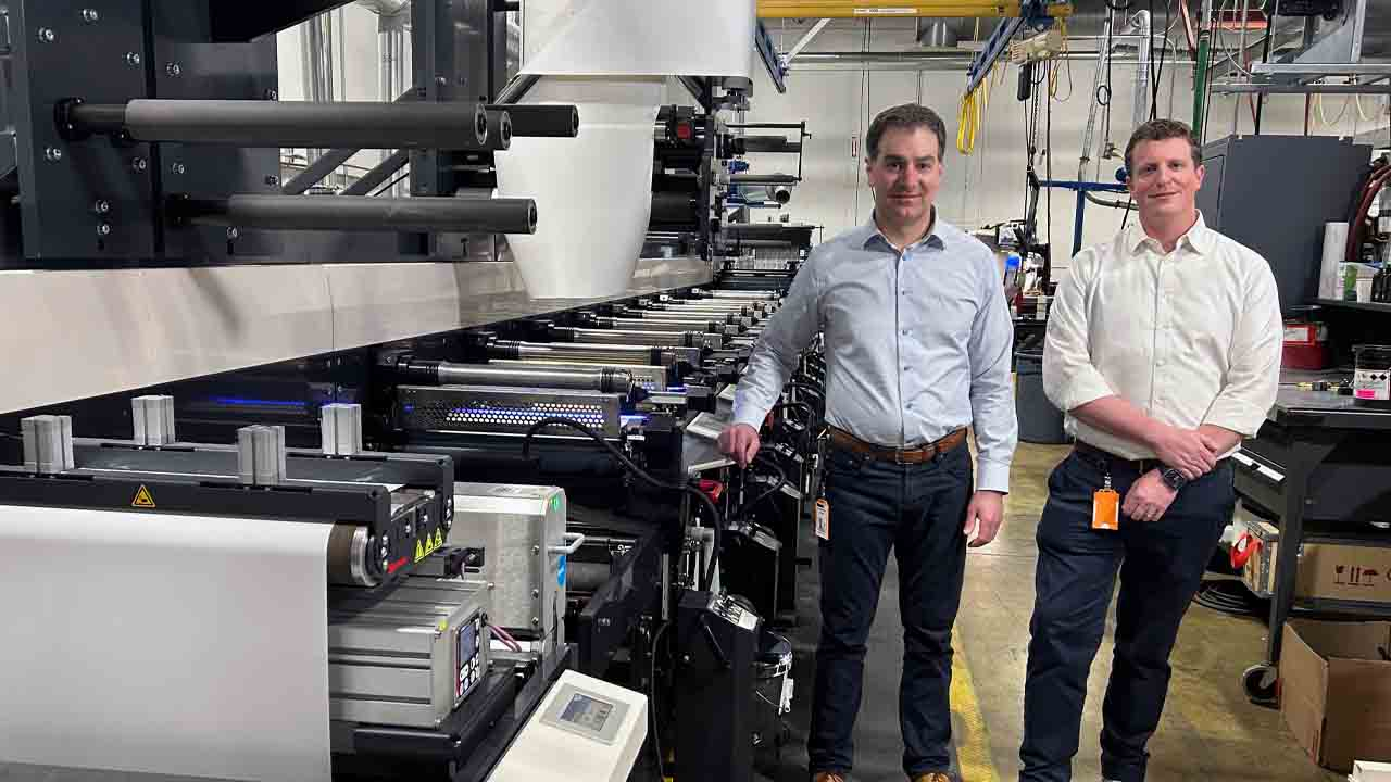 Chris Dillon and Michael Dillon alongside one of the three presses that have been upgraded to run UV LED curing.