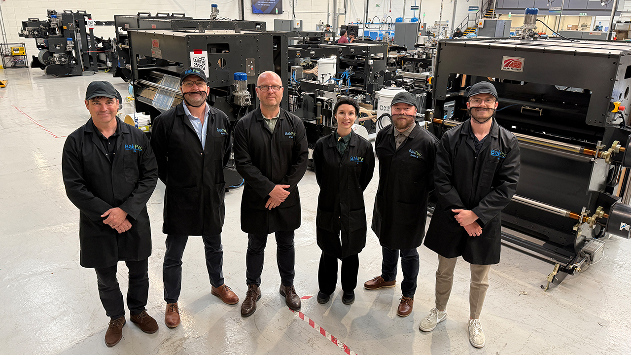 Management team stands on production floor surrounded by machinery