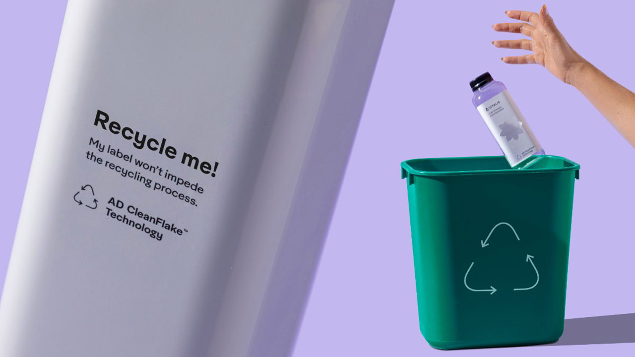 A bottle that says 'Recycle Me' next to a recycling bin