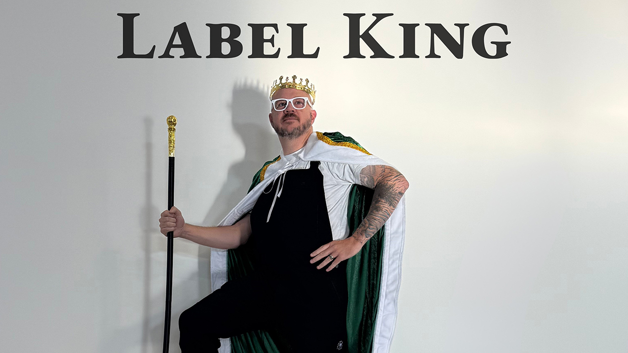 Adam Peek wearing a crown under a sign that says "Label King"