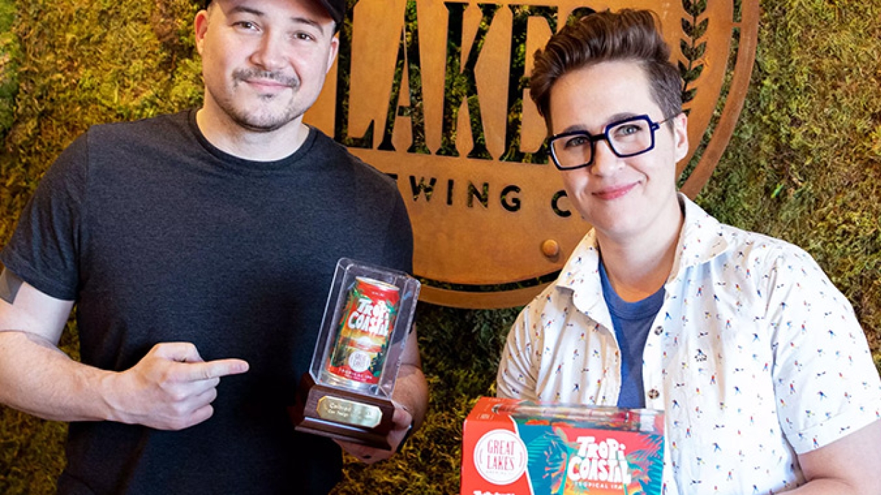 Great Lakes Brewing Company’s creative manager Jameson Campbell and brand marketing manager Marissa DeSantis show off 2022 Colored by INX Can Design Contest trophy with winning craft beer entry for TropiCoastal Tropical IPA