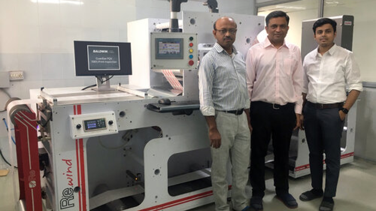 Bhavya Shah (left) and Manish Patel (right) of Shreedhar Labels with Amit Desai of Baldwin Vision Systems, and the Guardian PQV 100 percent inspection system installed on their Re brand rewinder.